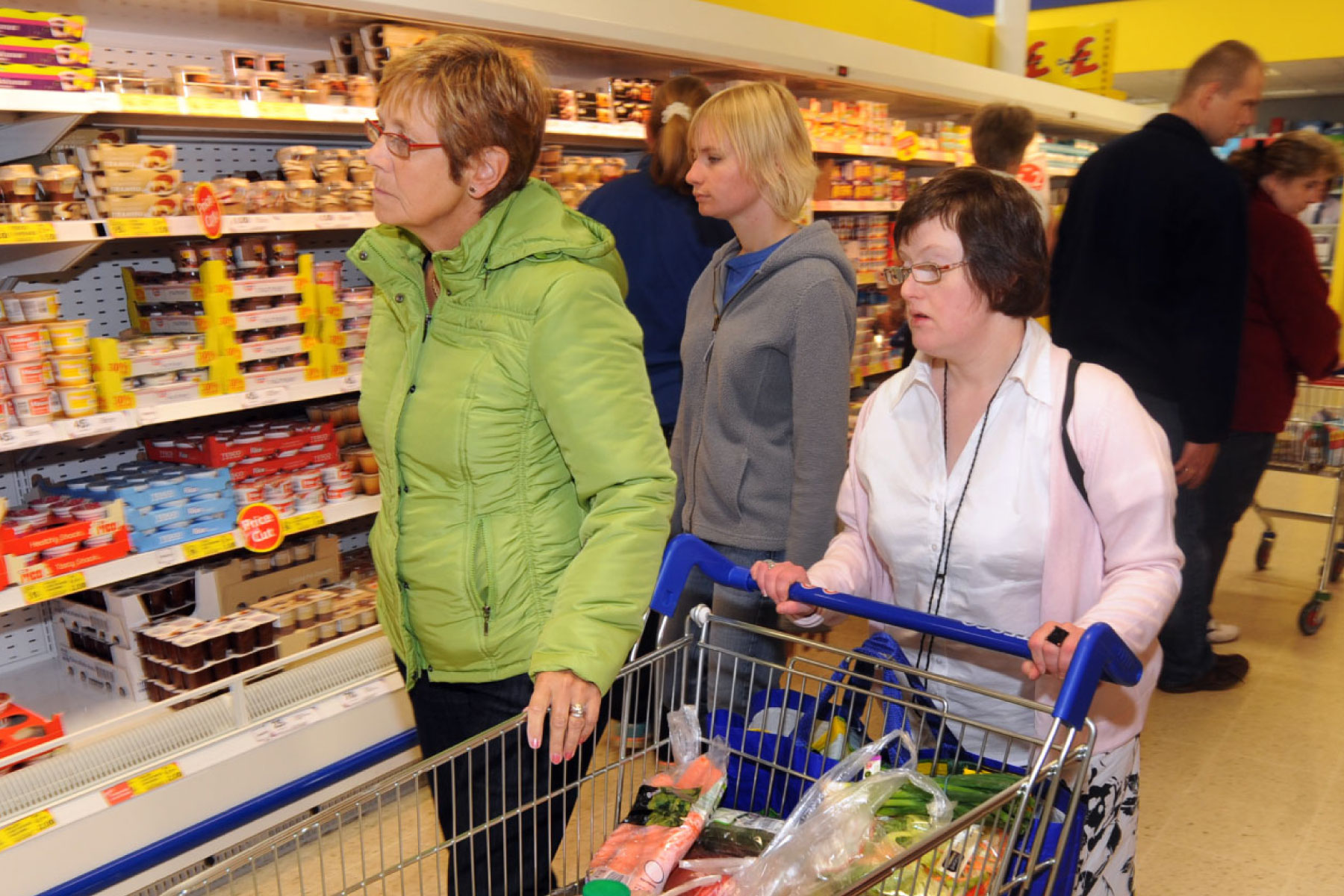 Professional carer helps two women with learning difficulties do their shopping